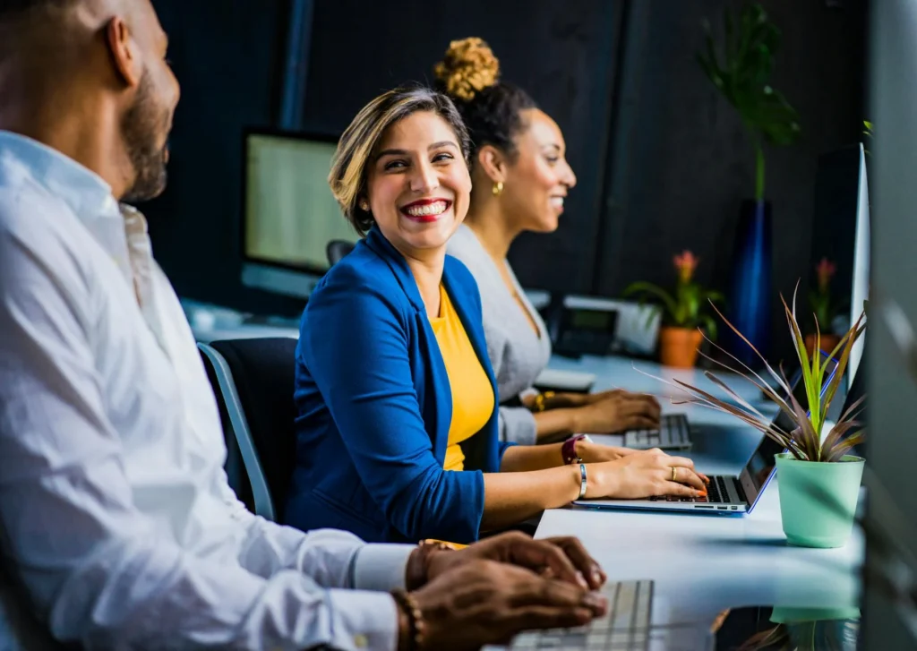 employees sitting at laptops smiling