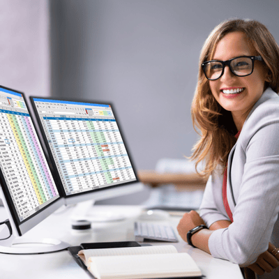 happy woman 2 monitors for data entry